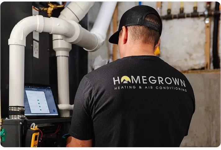 Homegrown Heating and Air Conditioning technician working at a furnace and its vent piping